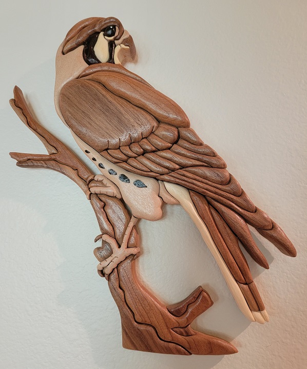 wood carved american kestrel perches on branch