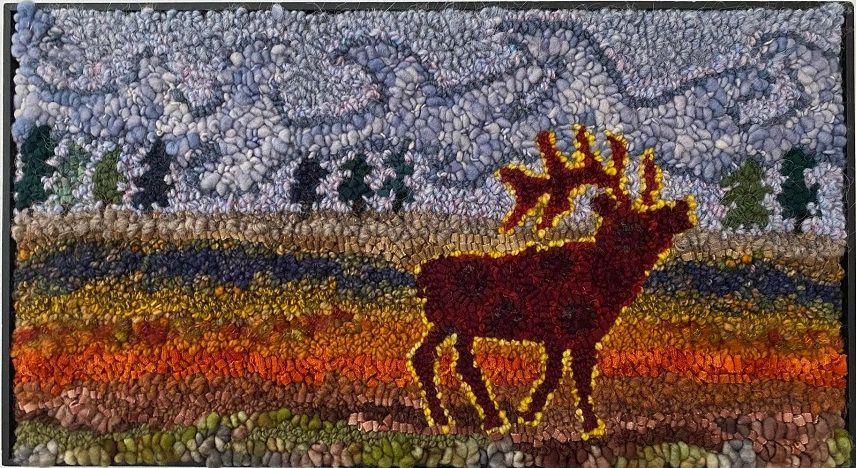 Looped fibre art with a brown elk encircled in a yellow glow in the forefront with a rainbow of colors on the ground, evergreen trees in the near distance, and blue mountains reaching the sky in far distance